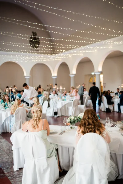 Blick über die festlich gedeckte Tafel im lichterkettengeschmückten Saal