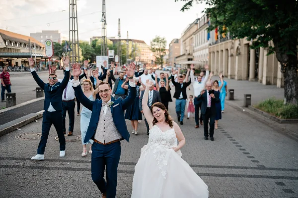 Brautpaar und Gäste ziehen jubelnd durch die Stadt