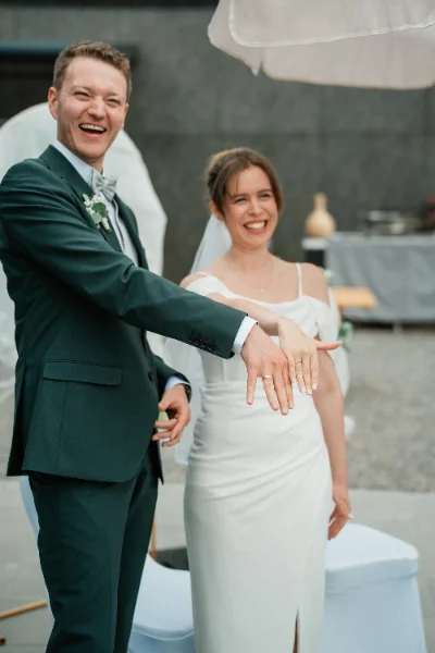 Frisch verheiratetes Paar lacht und zeigt die neuen Ringe