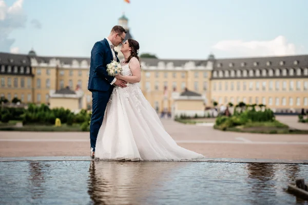 Brautpaar küsst sich vor dem Karlsruher Schloss und spiegelt sich im Wasser