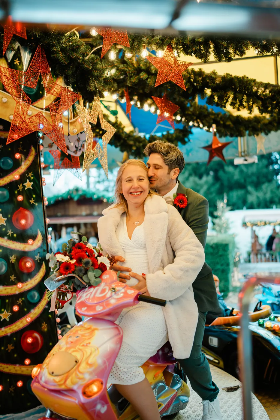 Brautpaar lacht auf einem Kinderkarussell auf dem Weihnachtsmarkt